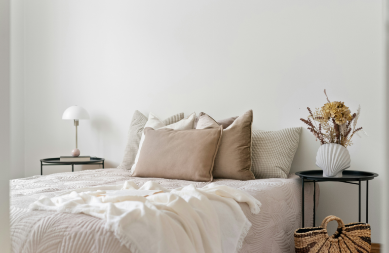 Styled cream bedroom with linen bedding soft lighting and a minimal bedside table