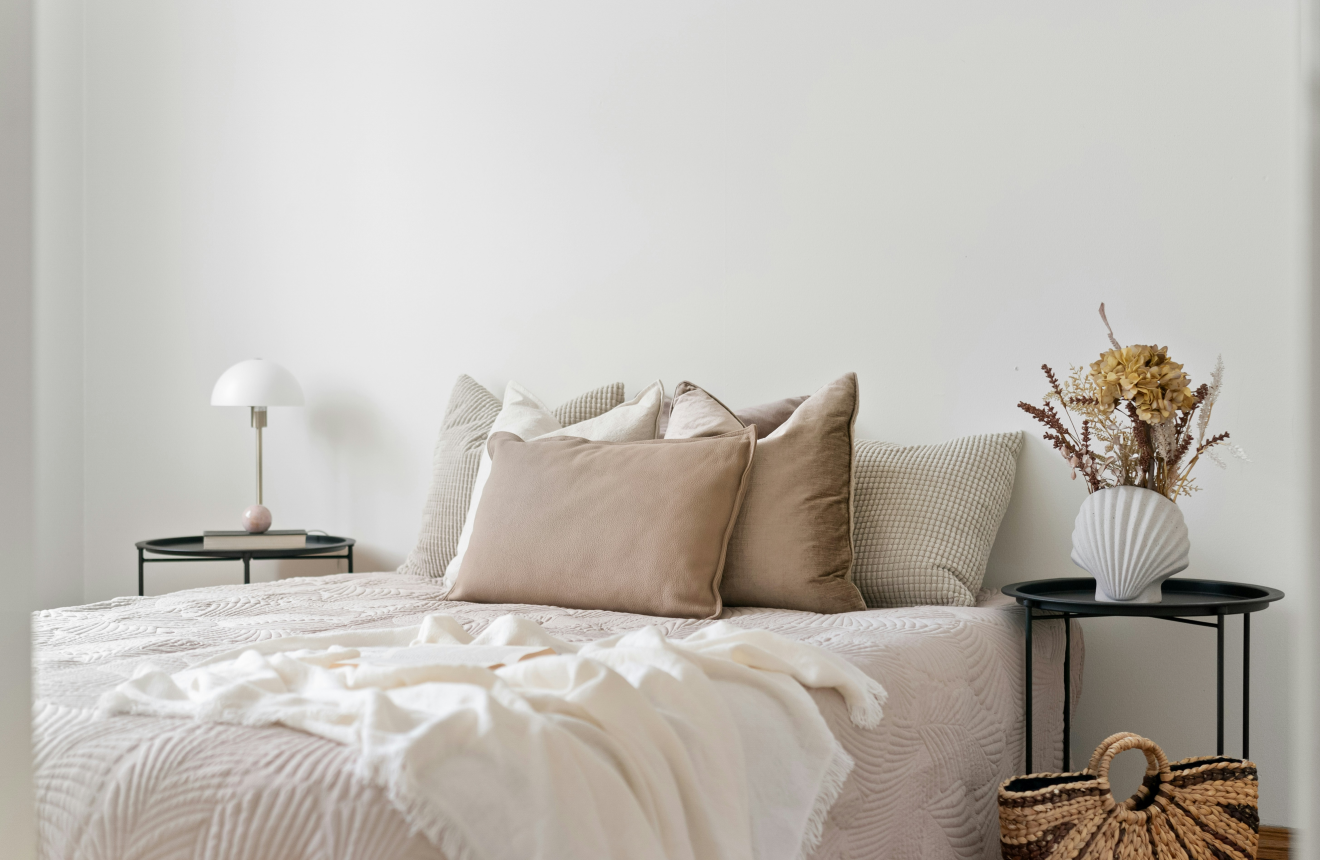 Styled cream bedroom with linen bedding soft lighting and a minimal bedside table
