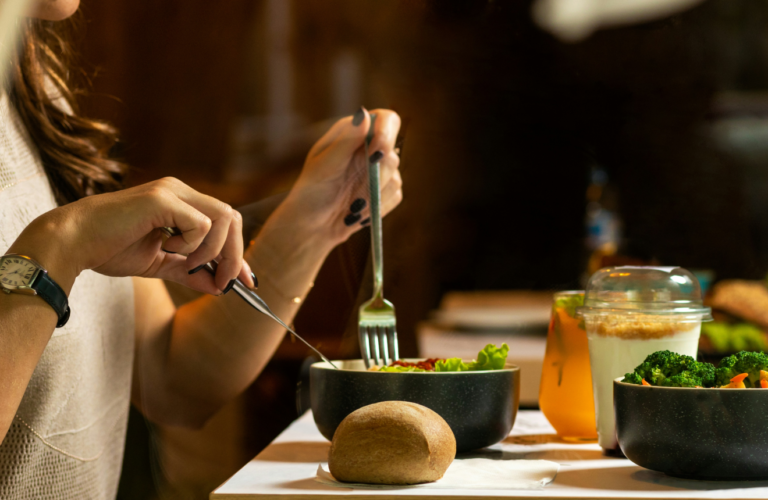 Woman sitting at a beautifully set table with candle and healthy meal practicing mindful eating