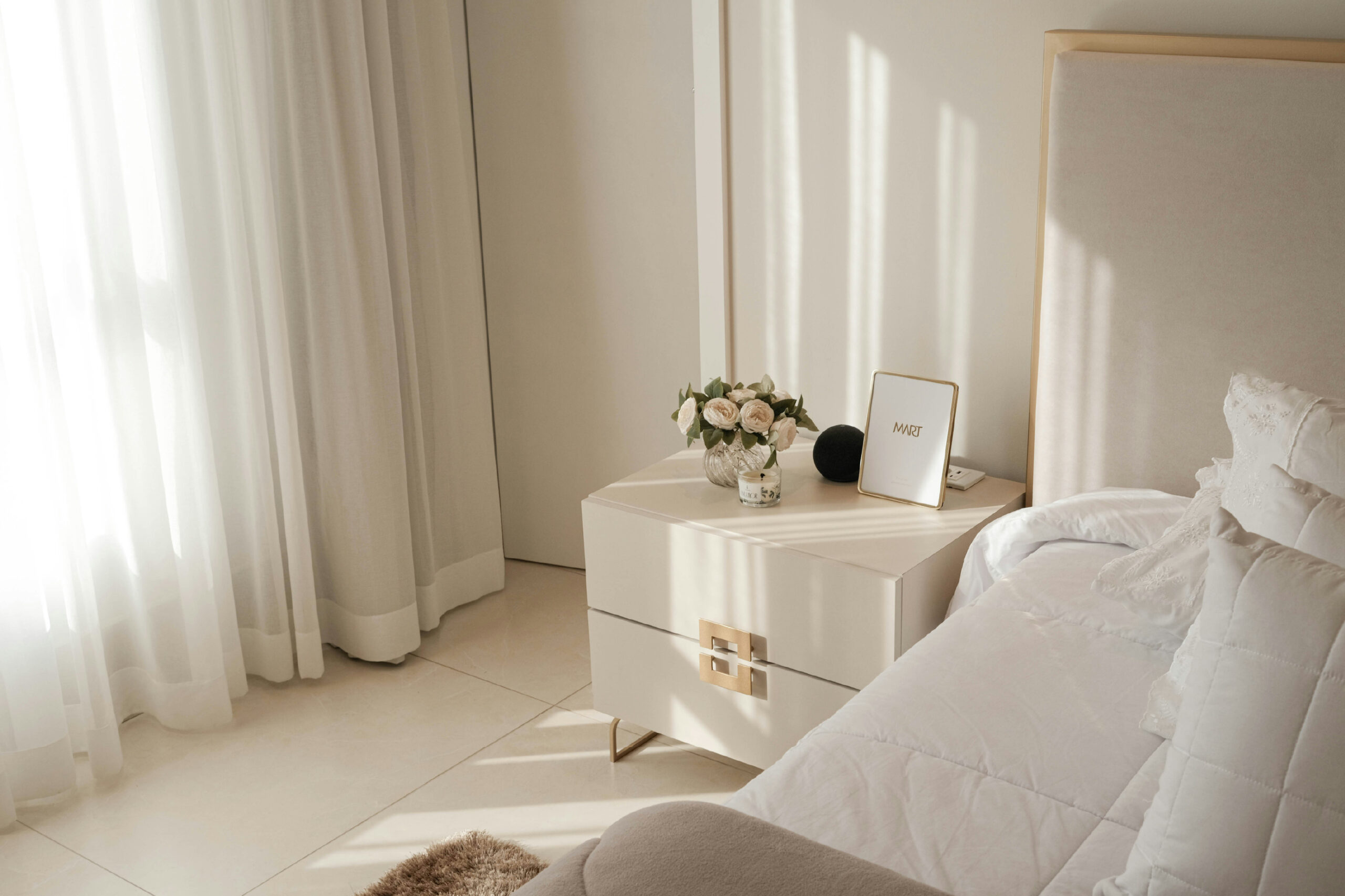 elegant cream bedroom with styled nightstand roses and natural light