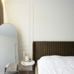 Small bedroom styled with large mirror light linen curtains and minimal furniture to feel bigger and more open