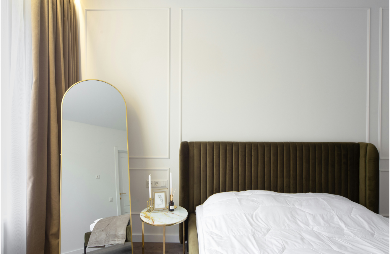 Small bedroom styled with large mirror light linen curtains and minimal furniture to feel bigger and more open
